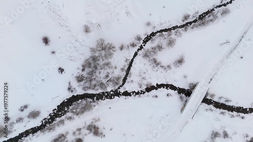 Snow blankets quiet winter forest with rocky stream