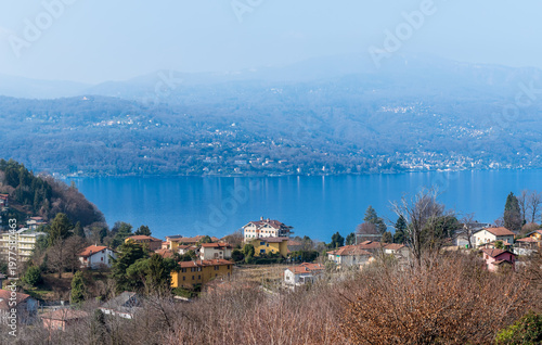 Wallpaper Mural Panoramic view of Lake Maggiore from the hilly area of Leggiuno, Lombardy, Italy. Scenic Italian landscape featuring lake waters, surrounding mountains, and residential settlement along the shoreline. Torontodigital.ca