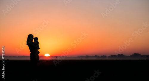Silhouette of a mother holding her baby during a beautiful sunrise