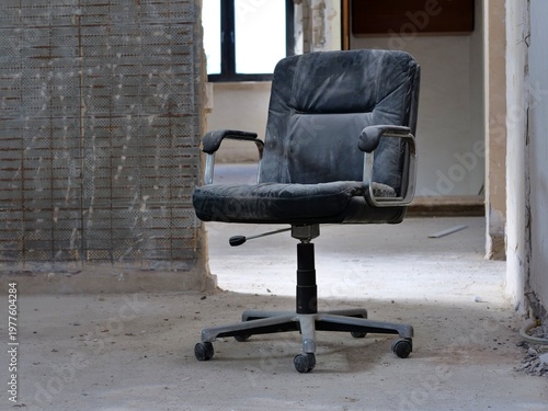 Foto dusty black office chair sitting in the middle of a
room under renovation
