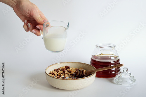 Breakfast with cereal flakes, milk, and honey on a white background.