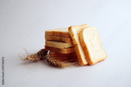 Sliced white toast bread and wheat ears on white background.