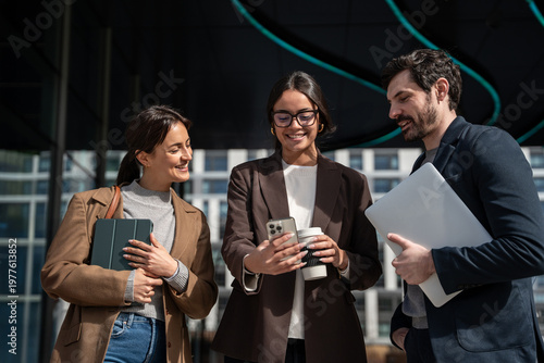 Business team collaborating outdoors with laptop and smartphone