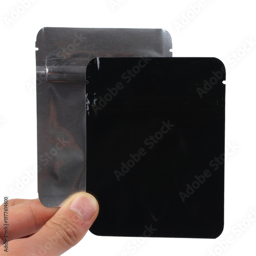 Hand holding two small black foil pouch bags for product packaging mockup