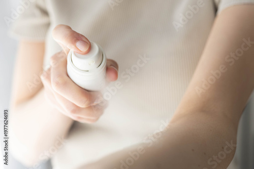 Closeup of a woman applying spray sunscreen.