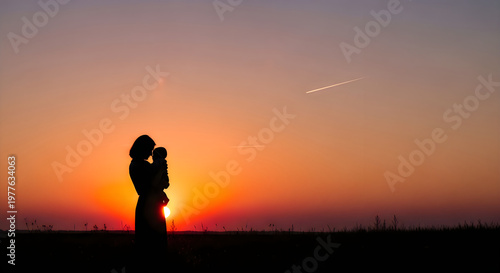 Silhouette of a mother holding her baby against a beautiful sunset sky