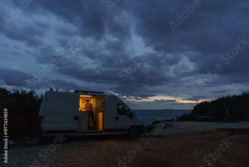 Camper van besides gravel road on the Adriatic Sea coast preparing for the night during blue hour in the evening, Himare, Albania