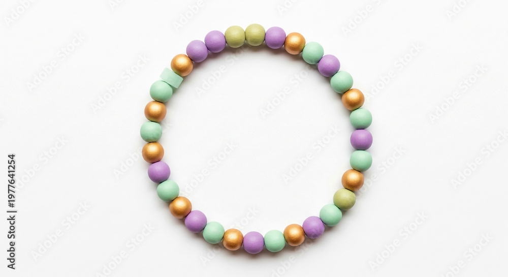 Fototapeta premium Handmade pastel beaded bracelet with gold accents arranged in a circle on a clean white background