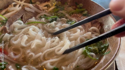 Eating Ramen noodles from Pho Bo dish at Vietnamese restaurant, delicious flavor