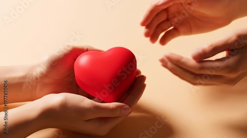 Hands passing a red heart symbol representing love and care.
