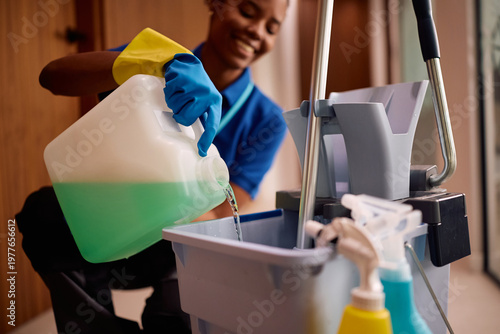 Photos Close up of professional cleaner using liquid detergent for floor mopping