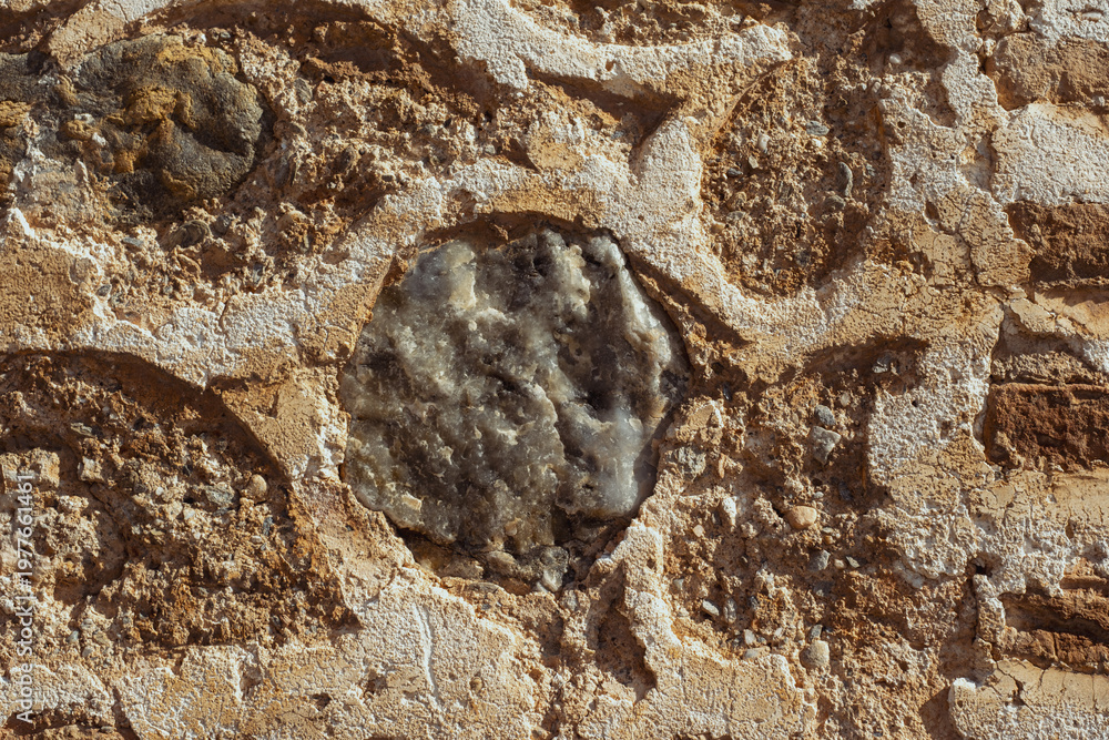 Obraz premium Close-up view of an old rugged stone wall, showing weathered texture, mortar, and a large round grey stone