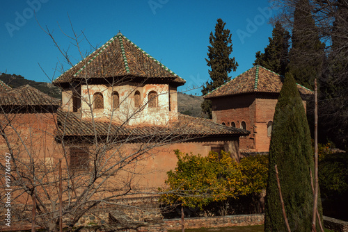 Alhambra palace architecture in granada, spain featuring traditional moorish design, tiled roofs, and cypress trees