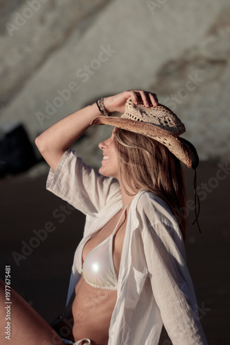 Woman smiling wearing cowboy hat and white shirt on beach