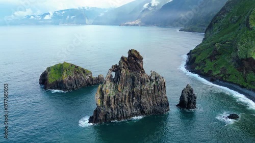 Majestic sea stacks rise from the turquoise Atlantic, framing Madeira's rugged, green coastline near Ribeira da Janela. A breathtaking natural spectacle.