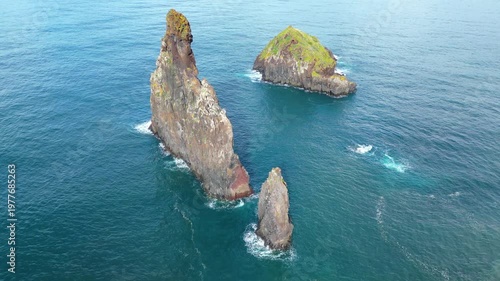 Dramatic sea stacks emerge from the vibrant Atlantic waters, highlighting the rugged beauty of Madeira's coastline under clear afternoon skies.
