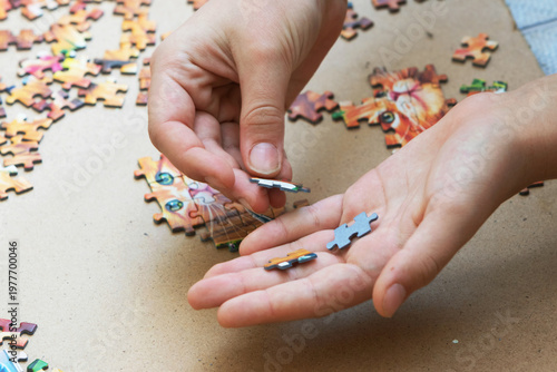 A teenage girl is putting together a puzzle. Only her hands are visible.