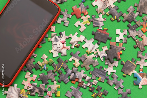 A mobile phone and puzzle pieces scattered on the floor in natural light