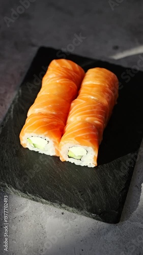 Delicious salmon sushi rolls served on a sleek black slate plate in a sunlit setting