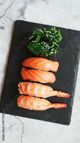Exquisite sushi platter showcasing vibrant salmon, shrimp, and fresh greens on a sleek slate surface