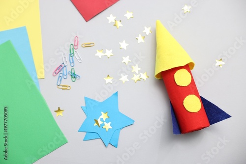 Handmade rocket and art materials on light background, flat lay