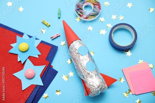 Handmade rocket and art materials on light blue background, closeup
