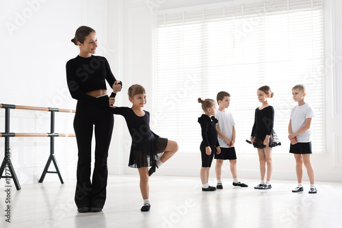 Φωτογραφία Professional dance teacher helping little girl during class in studio