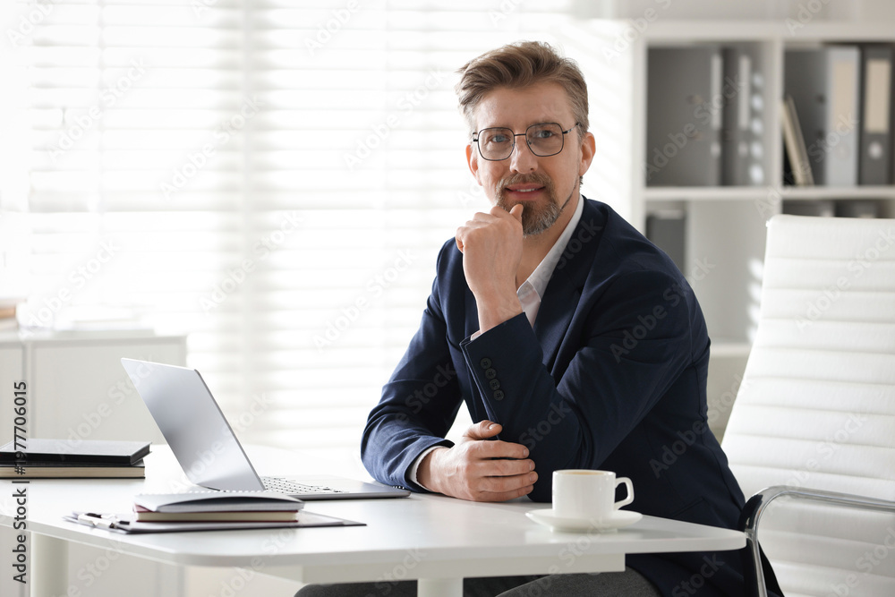 Naklejka premium Portrait of handsome businessman at white desk in office