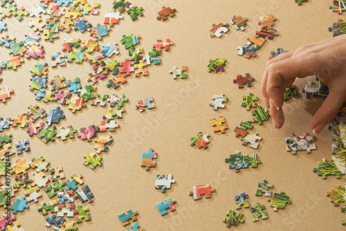 A woman is assembling puzzles at home in natural light. Only hands are visible.