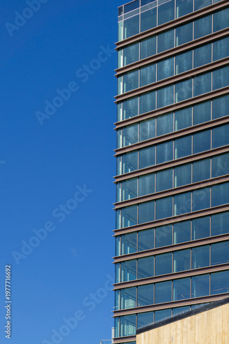 Modern Glass Skyscraper Facade with Horizontal Bronze Framing Against a Clear Blue Sky