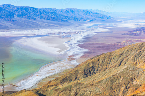 Vivid mineral-rich salt flats and Badwater Basin stretch below rugged mountains, seen from Dante’s View in Death Valley.