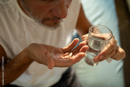 Man taking pill with water at home