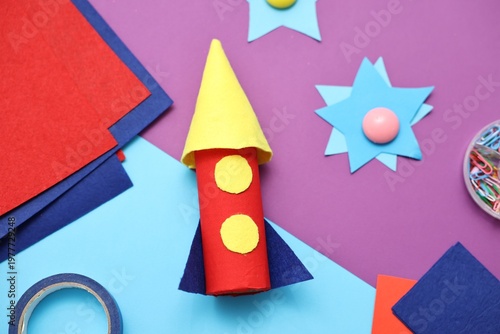 Handmade rocket and art materials on color background, flat lay