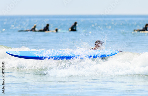 фотографія A surfer falls into the ocean as their blue surfboard splashes through a wave, capturing an action-packed surfing wipeout moment