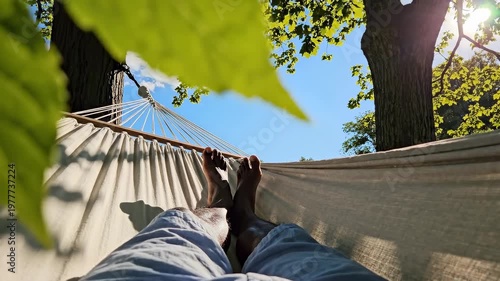 Relaxed person lying in a hammock between trees on a sunny summer day, feet up and sky above, creating an outdoor leisure scene for отдых, travel, wellness and weekend relaxation content