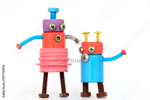 Two colorful handmade robot toys made from recycled materials including screws, bolts, springs, and plastic bottle caps. Creative DIY concept representing recycling, sustainability, imagination