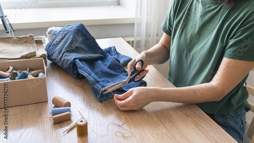 Φωτογραφία Hands cutting thread from old jeans for reuse, promoting sustainable fashion and circular economy principles