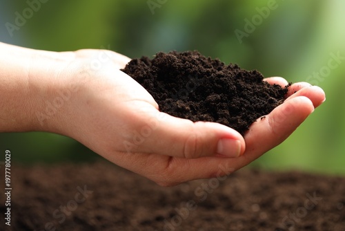 Woman with fresh soil on blurred background, closeup