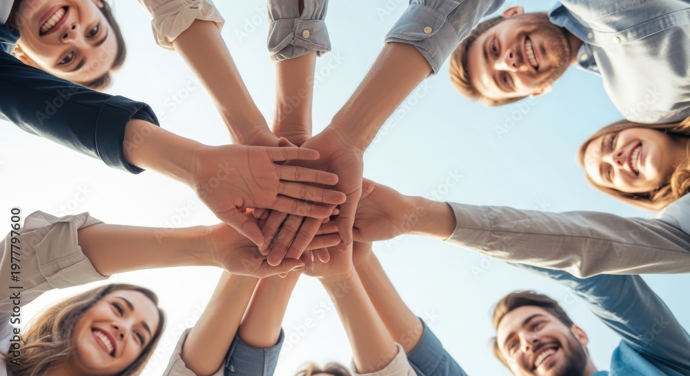 Obraz premium Diverse group of happy young people joining their hands together in a circle to show unity and teamwork.
