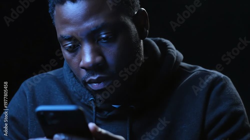 Man illuminated by smartphone screen in dark, focused on mobile device