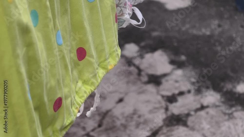 Close up of a green polka dot fabric with yellow trim hanging outdoors in daylight