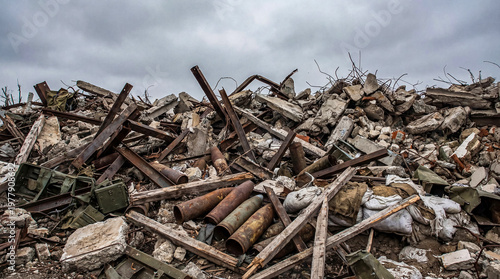 Tableau sur toile Massive pile of war-torn debris, including concrete, twisted metal, and discarded artillery shells, under a cloudy sky