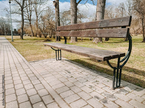 Empty Park Bench Along Path in Quiet Spring City Park
