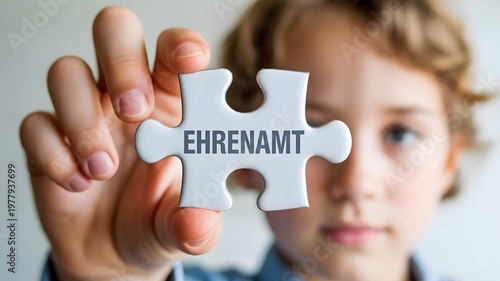 A young person displays a puzzle piece with the word EHRENAMT symbolizing volunteering and community service