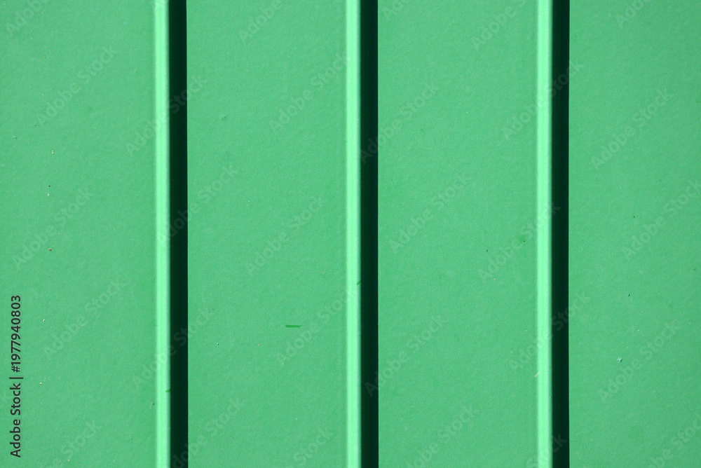 Fototapeta premium Green corrugated metal texture background surface with vertical ridges and shadows