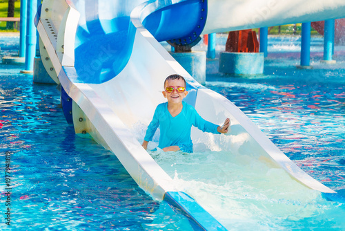 Fotografie happy cute child boy rides a water slide in a water park in summer vacation