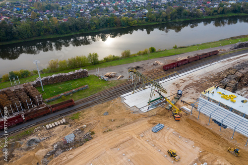 A crane is working at the construction site of a factory under construction top view