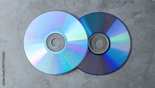Two Shiny CDs or DVDs on a Gray Concrete Background.