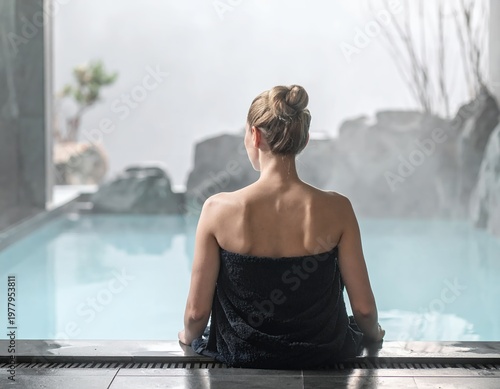 Woman in towel relaxing in a luxurious spa pool with a scenic view.