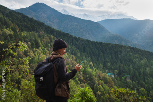Female hiker using smartphone in mountains, travel and navigation concept.